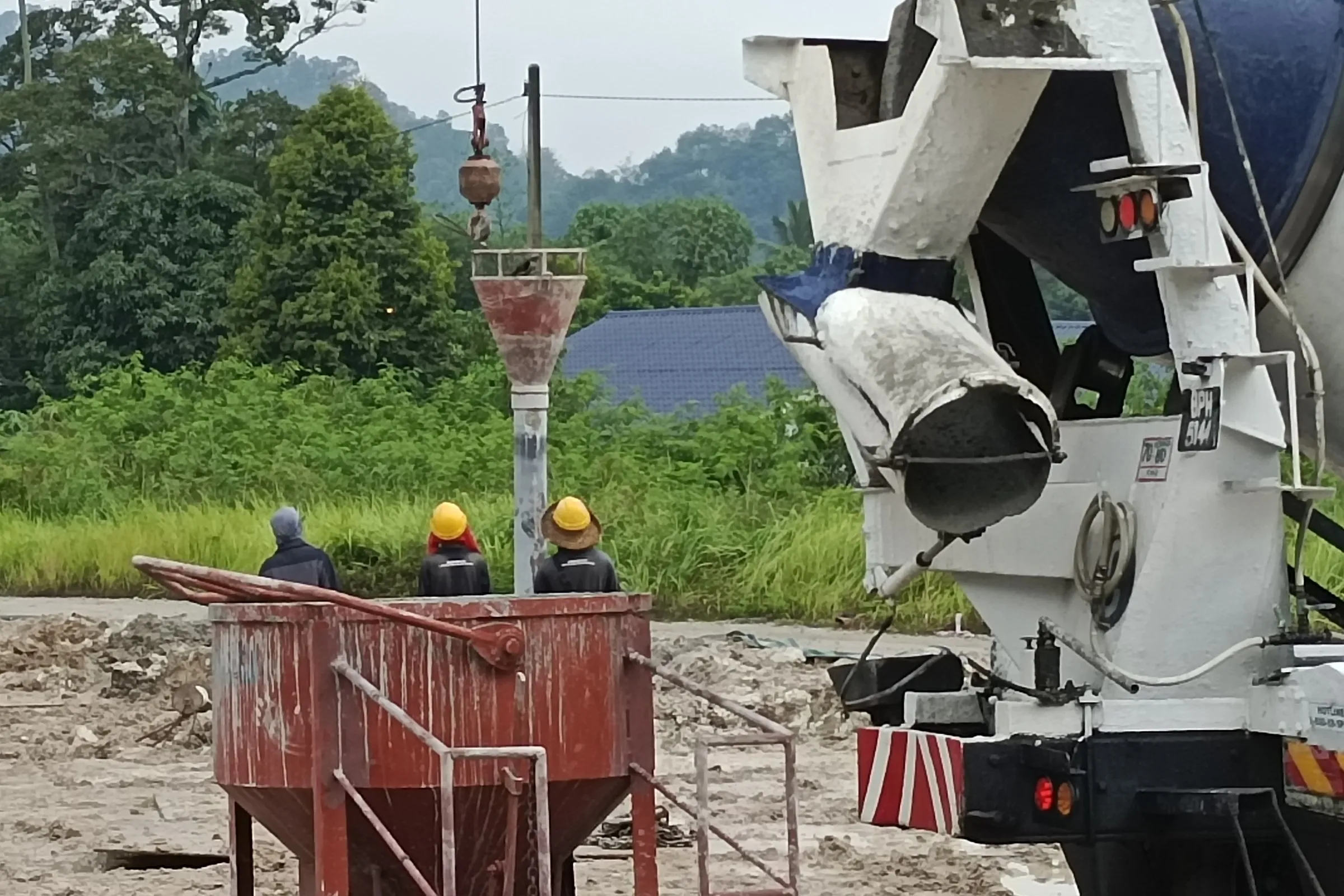 Samamaju site crew at a tremie hopper as a mixer truck pours concrete for a bored pile
